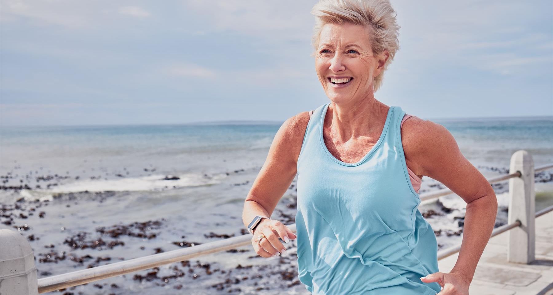 A woman runs beside the sea.