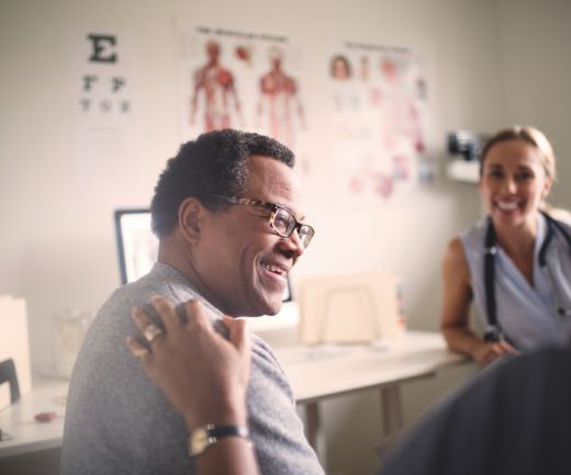 A smiling patient talks to a doctor.
